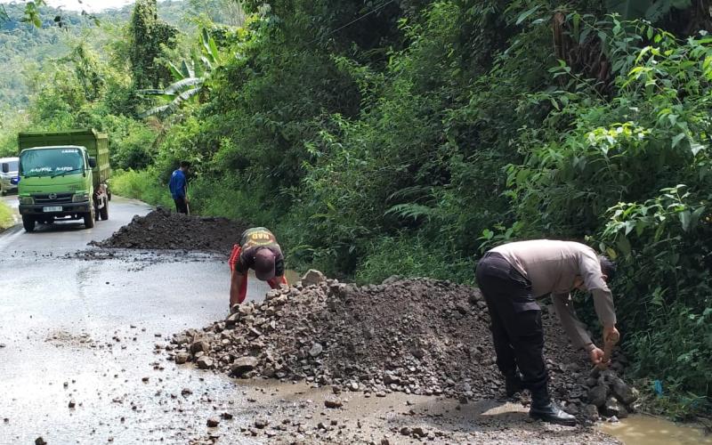 Sambang, Bhabinkamtibmas Polsek Rimbo Pengadang Bersihkan Material Longsor dan Timbun Jalan Berlubang