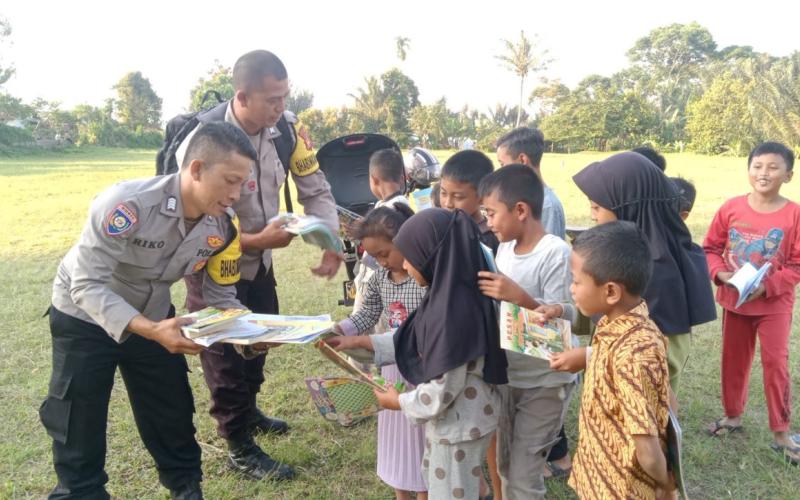 Tingkatkan Literasi, Bhabinkamtibmas Polsek Sindang Kelingi Bagikan Buku Bacaan Kepada Anak-anak