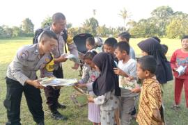 Tingkatkan Literasi, Bhabinkamtibmas Polsek Sindang Kelingi Bagikan Buku Bacaan Kepada Anak-anak